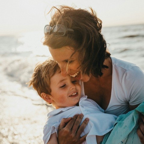 a woman holding a child on a beach