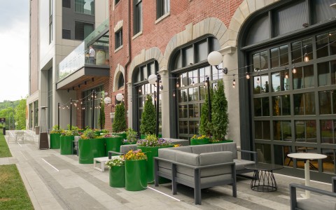 a patio with a brick building and a patio with a sofa and plants