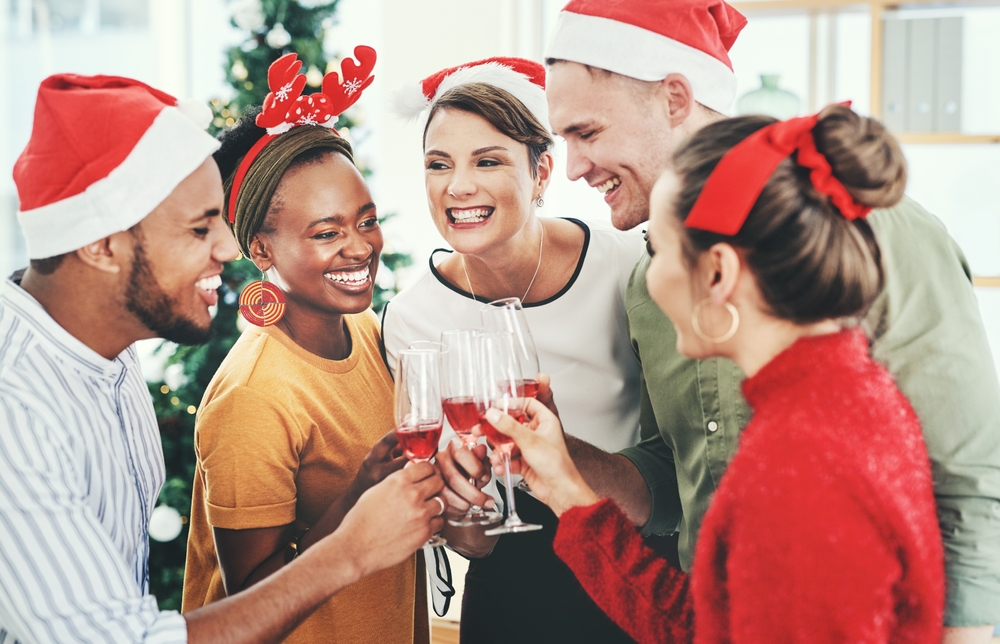 a group of people wearing santa hats and holding wine glasses