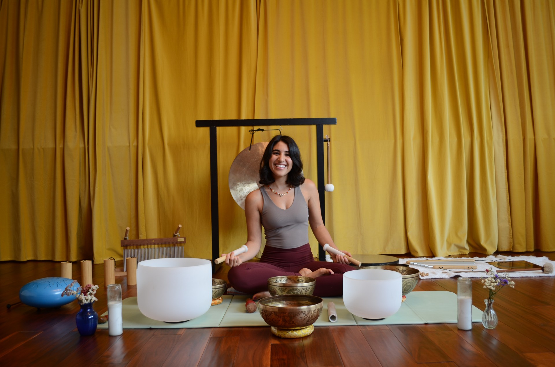 a woman sitting in a yoga pose with singing bowls