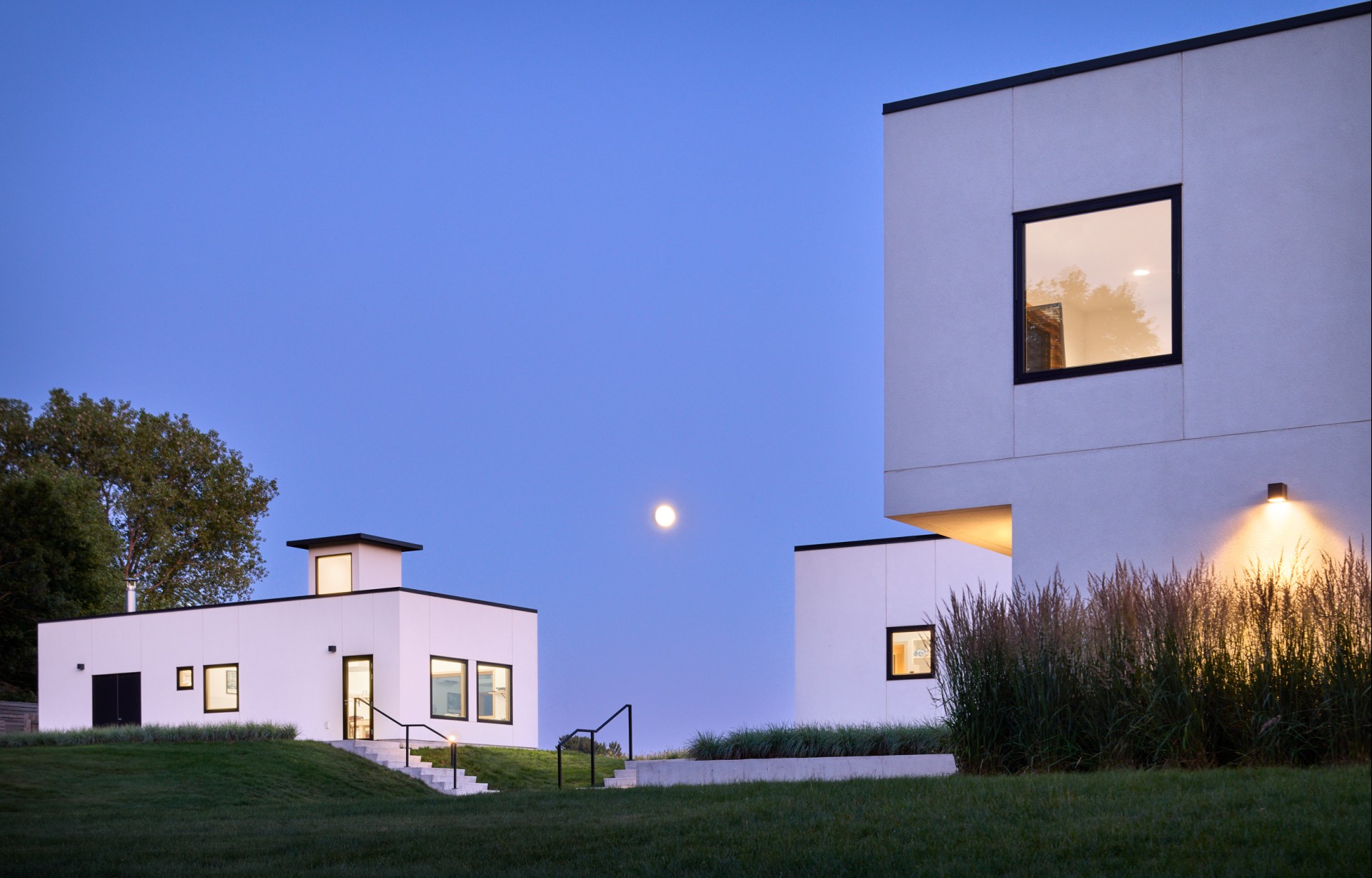a white building with windows and stairs leading to the ground