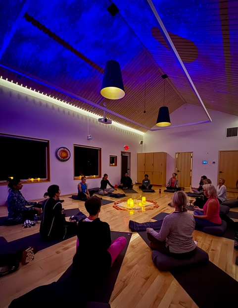 a group of people sitting on mats in a room with lights