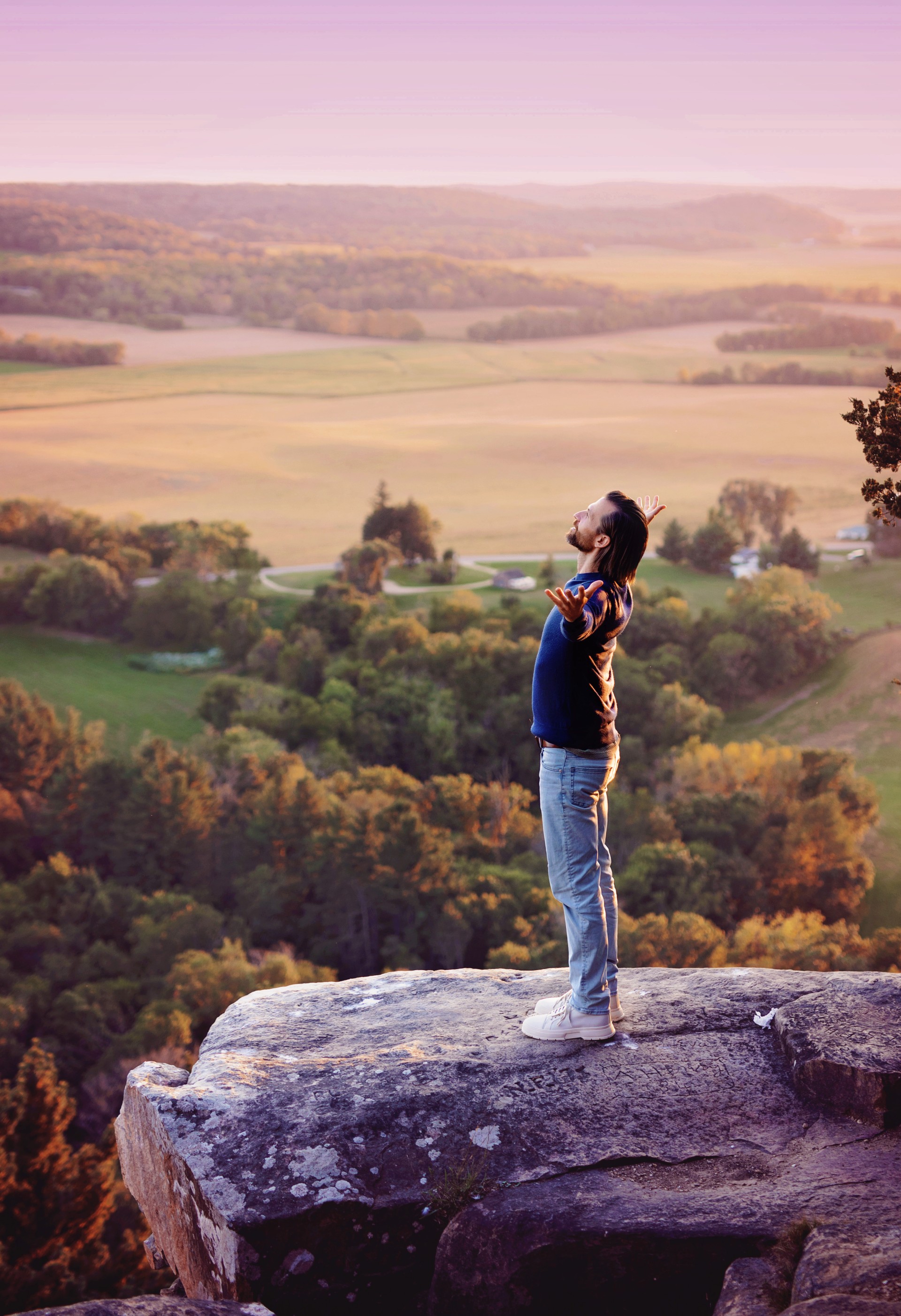 a man standing on a rock with his arms raised