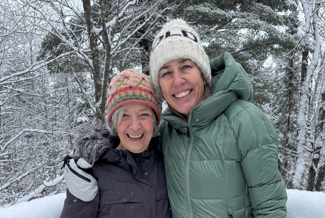 two women standing on a fence in the snow