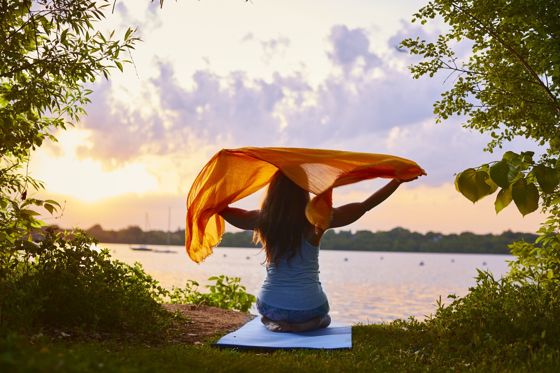 a woman sitting on a mat with a scarf over her head