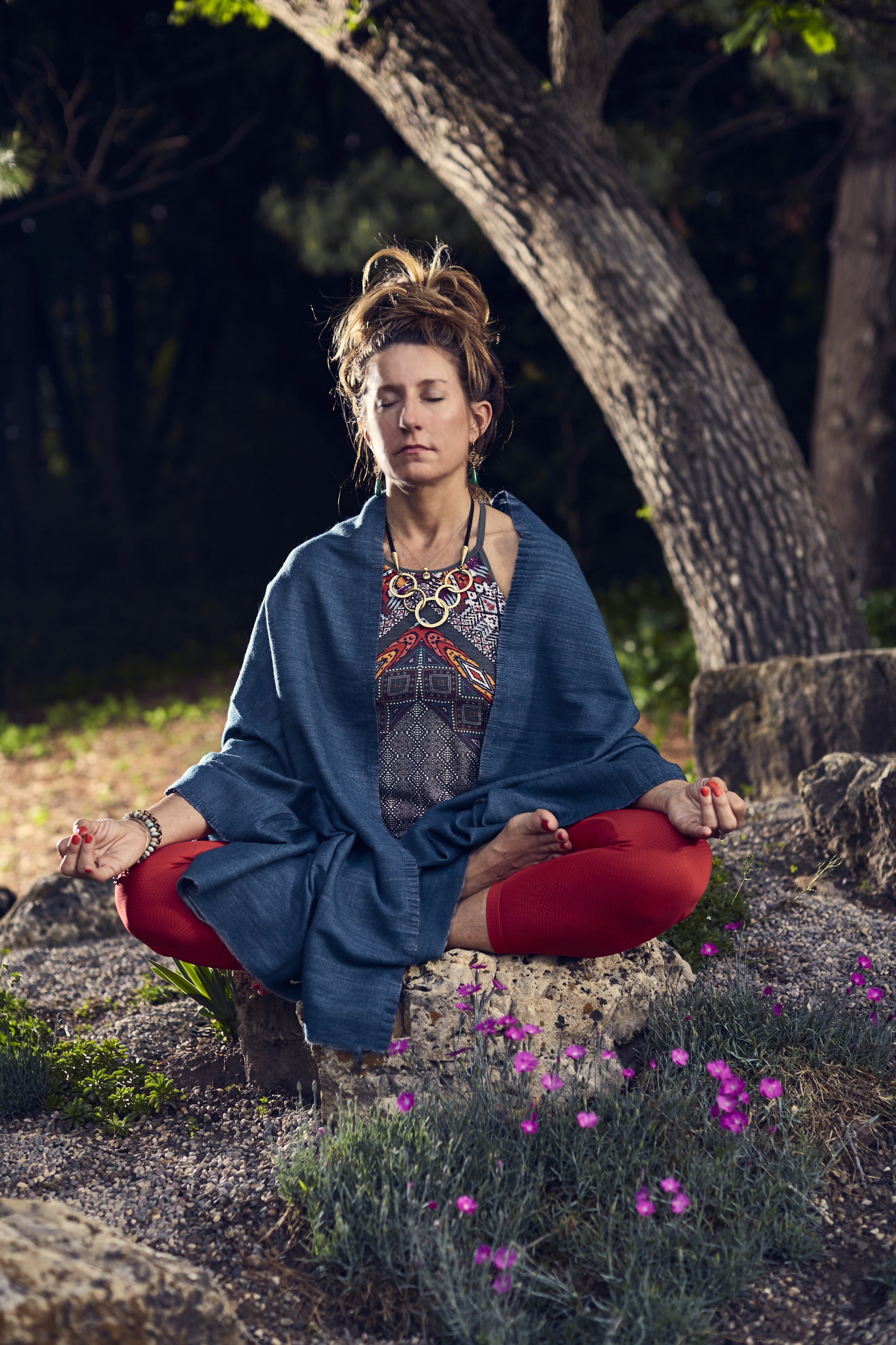 a woman sitting on a rock with her eyes closed