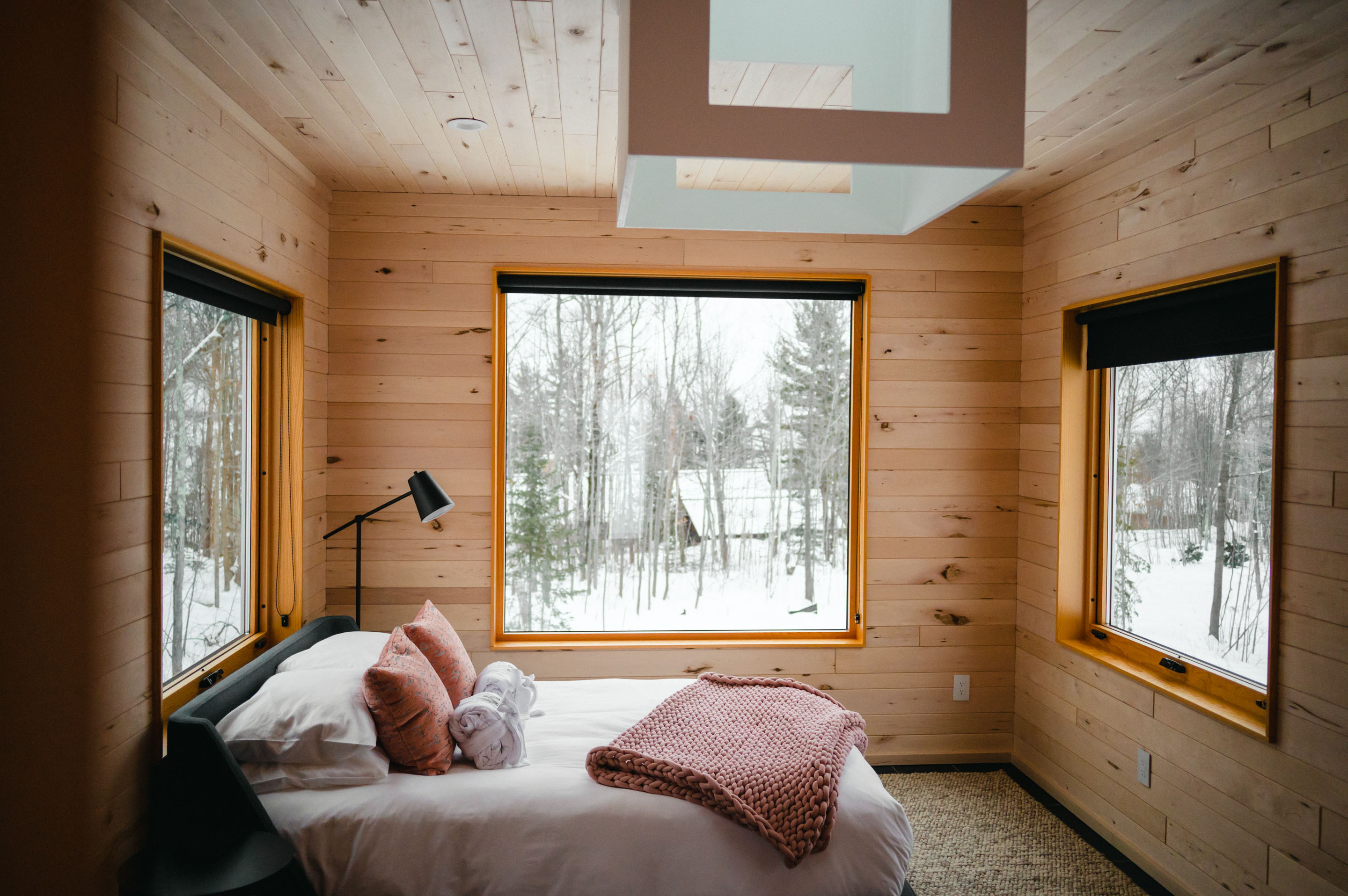 a bed in a room with windows and trees outside