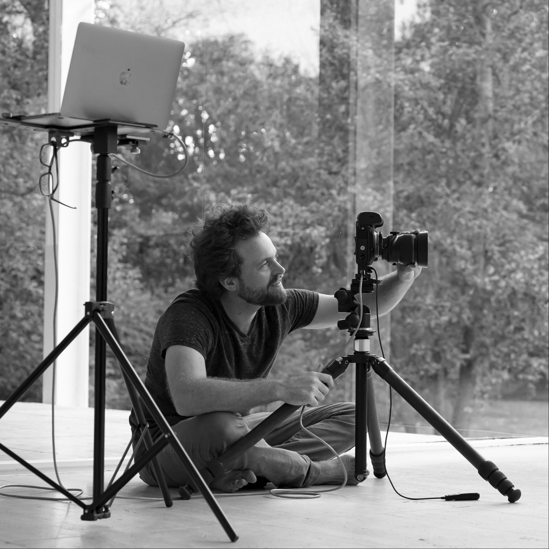 a man sitting on the floor with a camera on a tripod