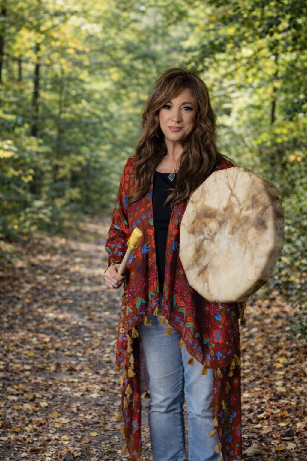 a woman holding a drum in a forest