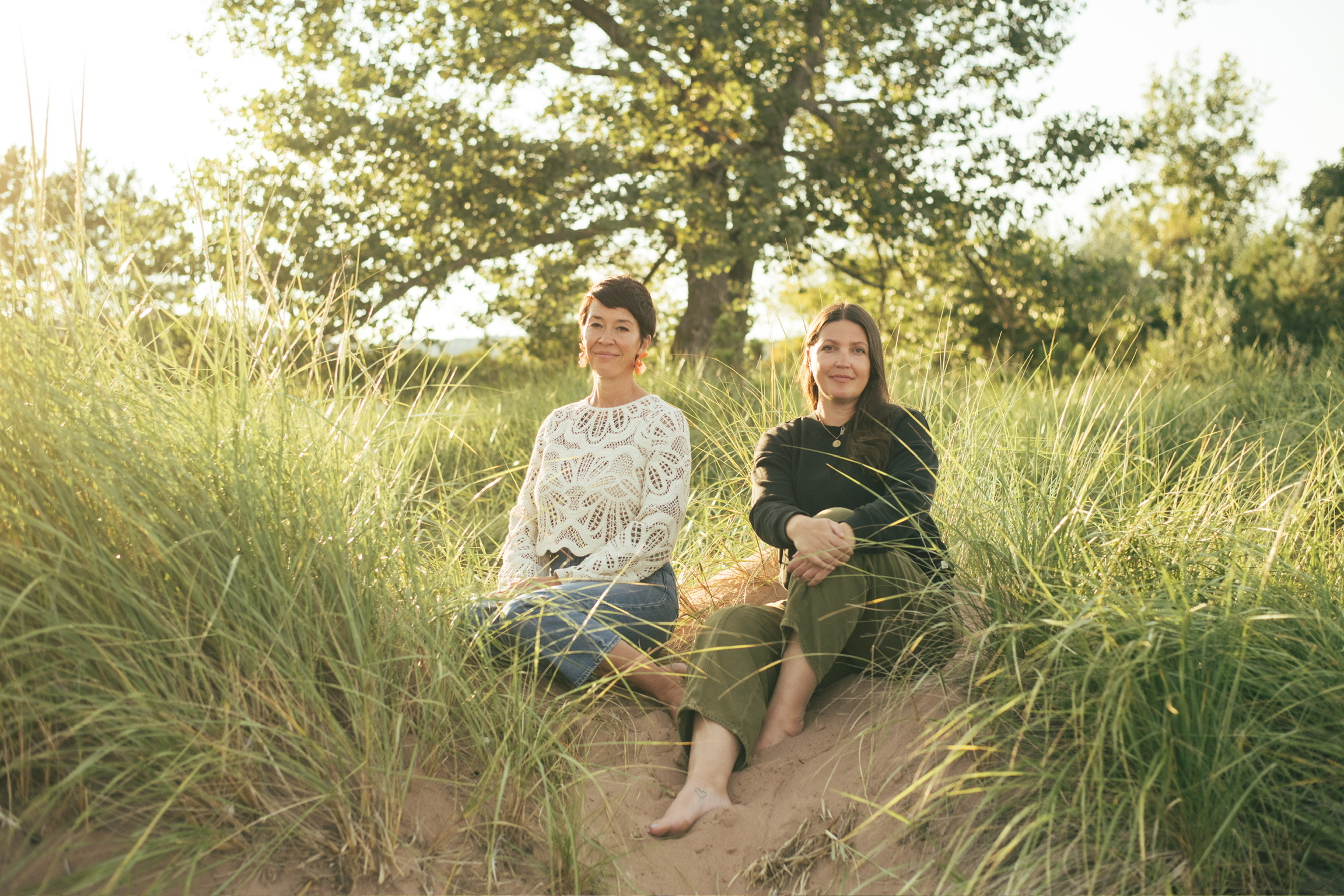 two women sitting in a grassy area