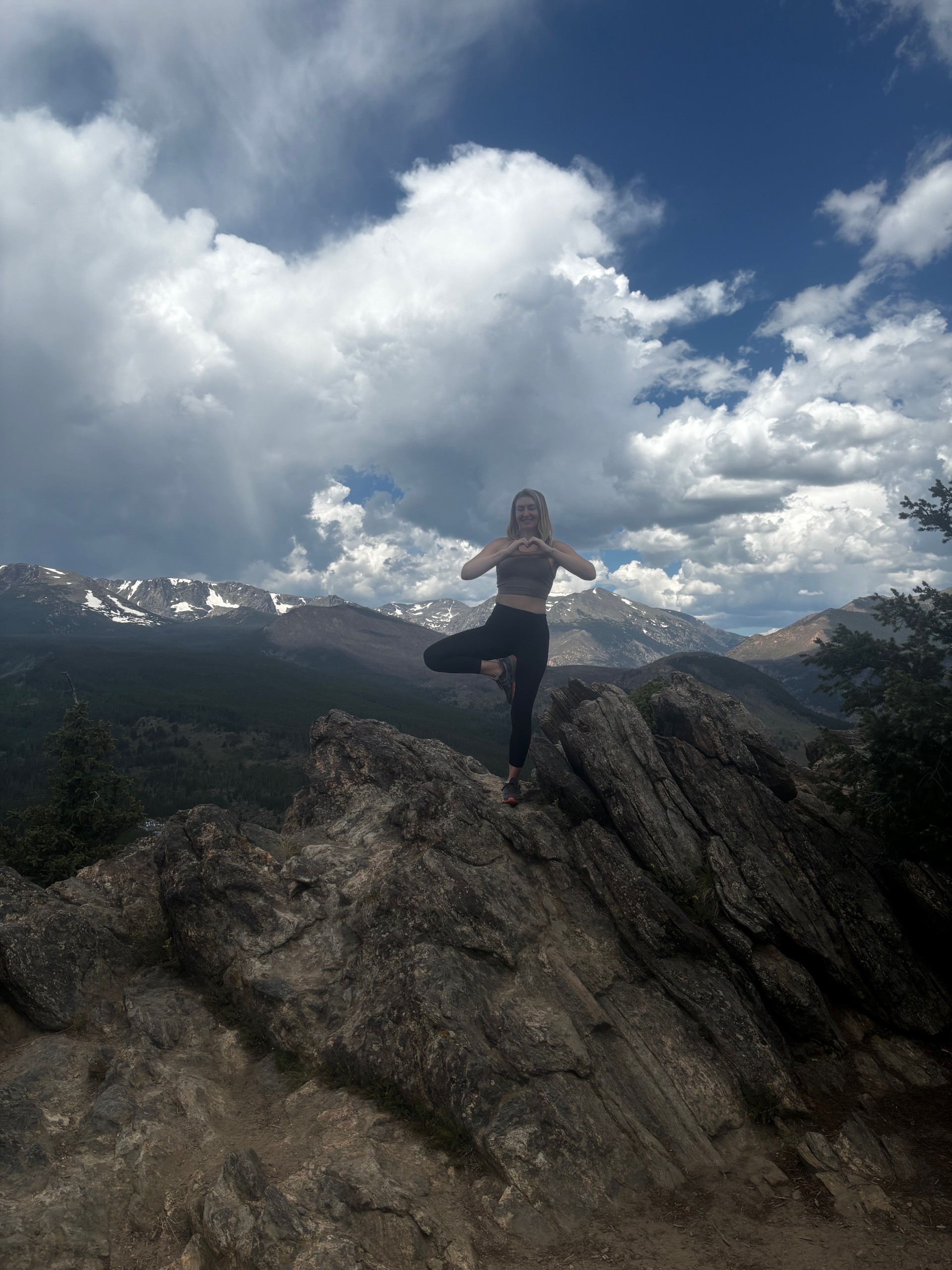 a woman standing on a rock with mountains in the background