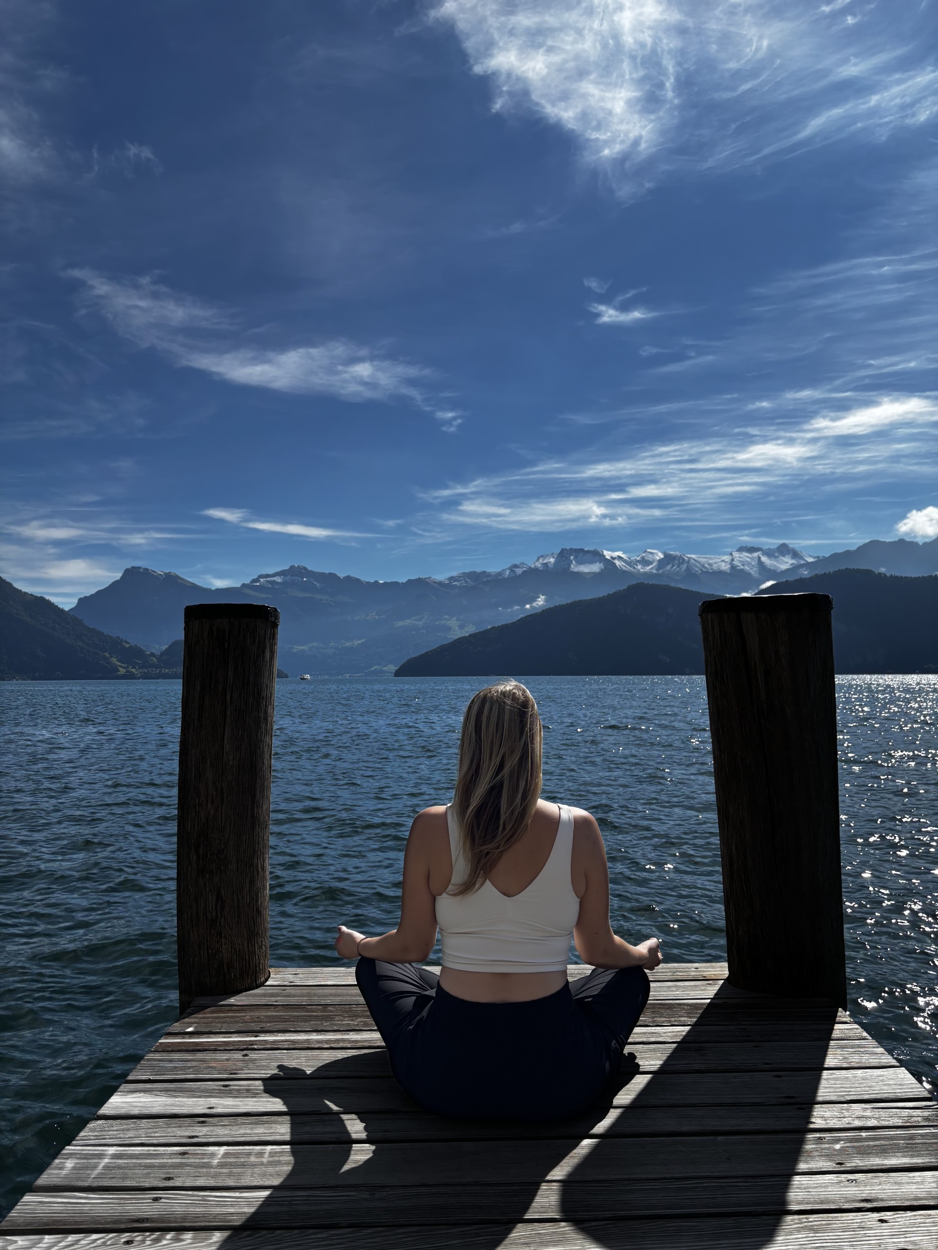 a woman sitting on a dock overlooking a body of water