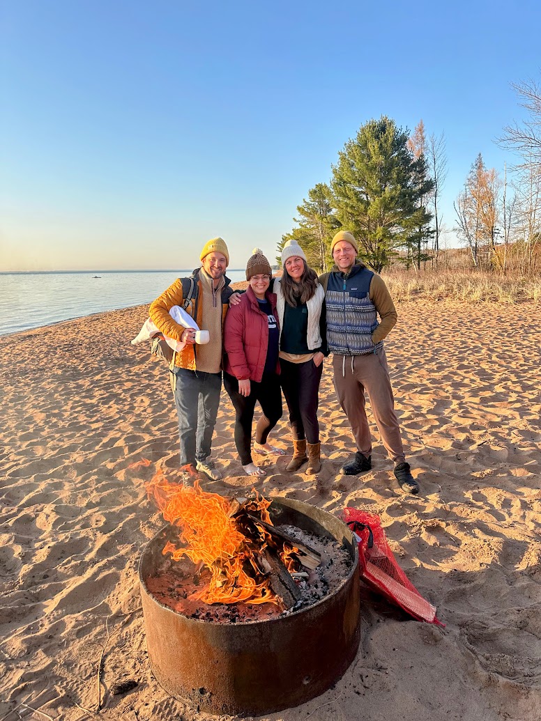 a group of people standing in front of a fire pit on a beach