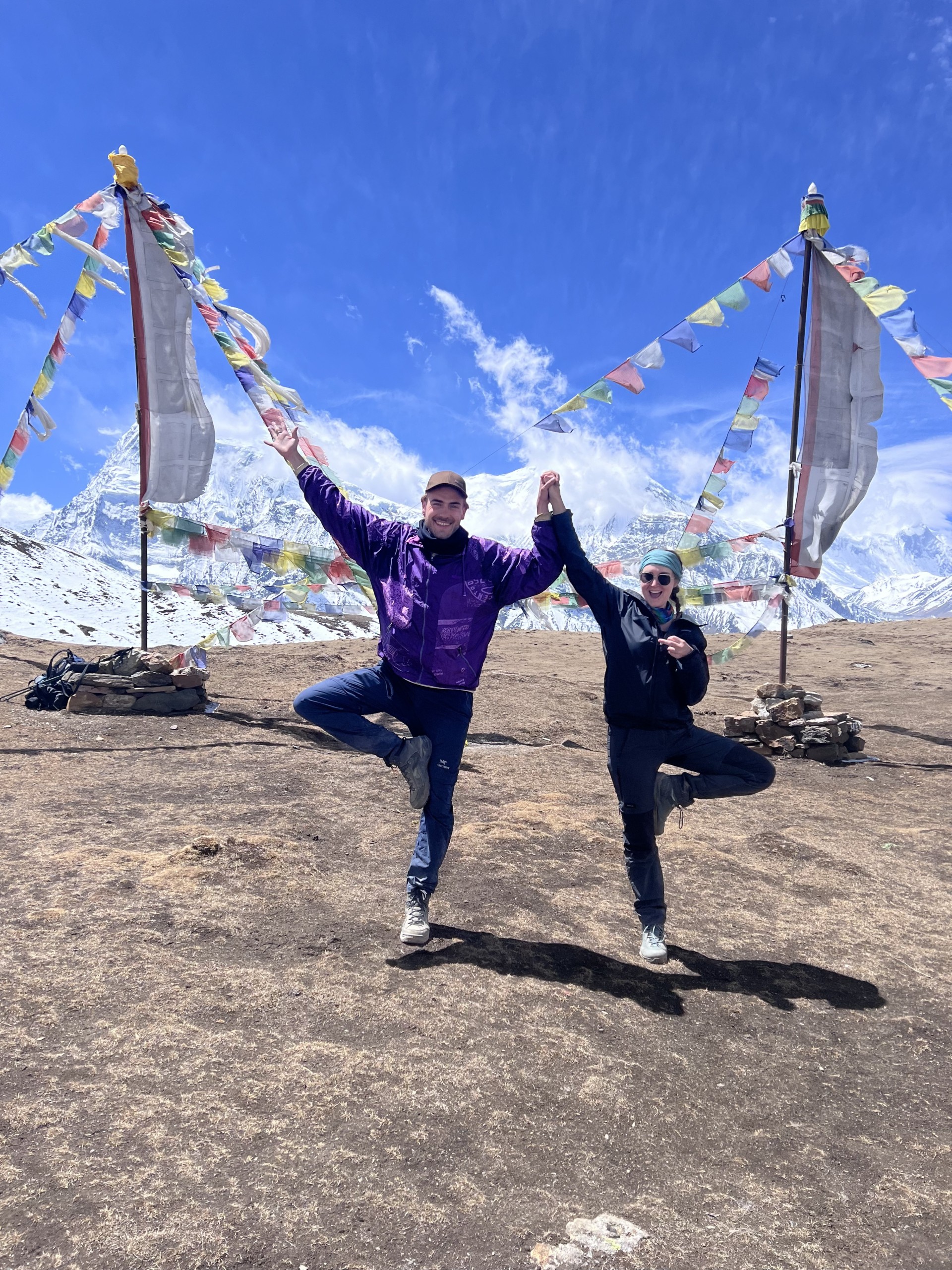 a man and woman standing on one leg with arms raised in the air