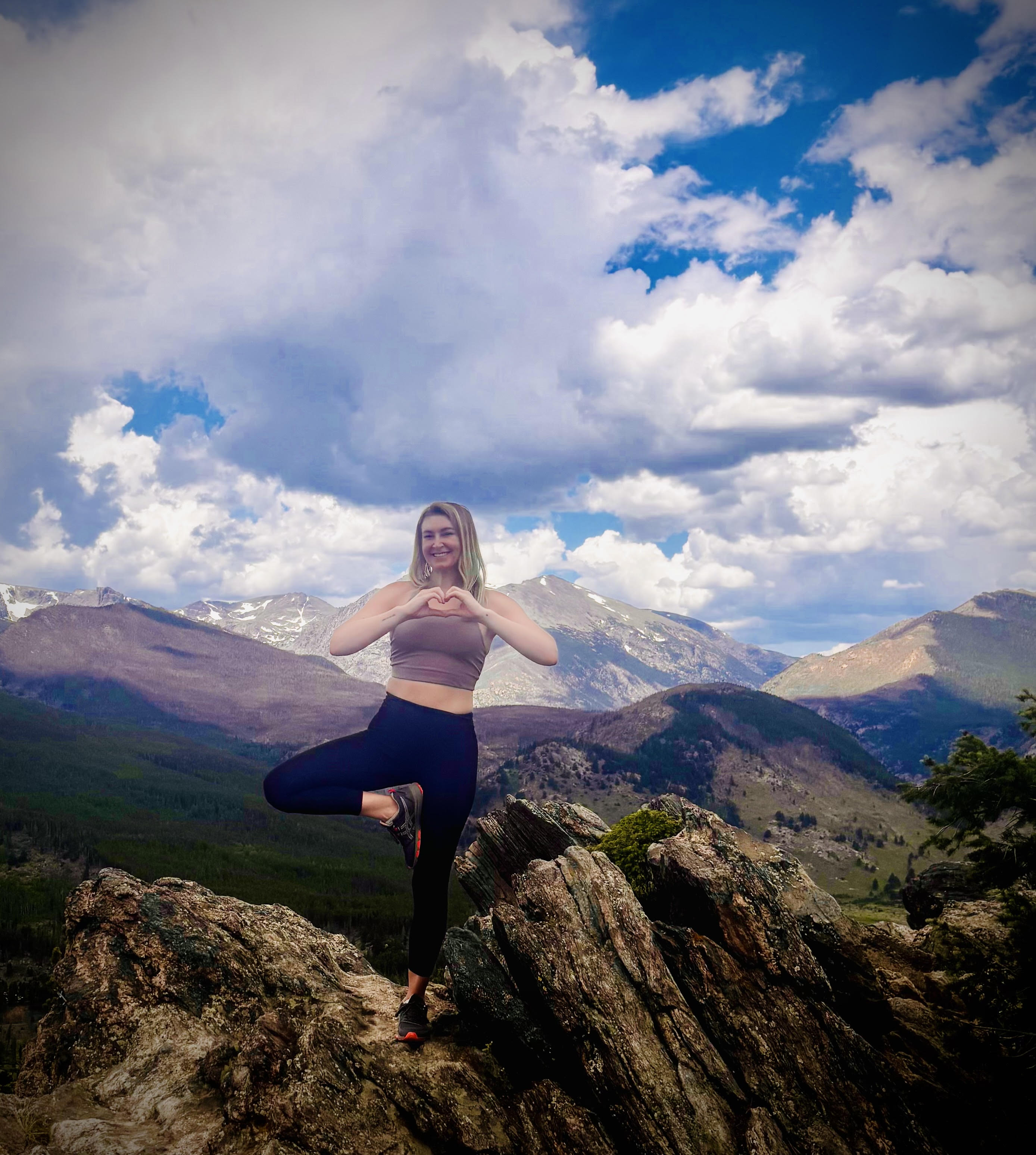 a woman standing on a rock with her hands in the middle of her chest