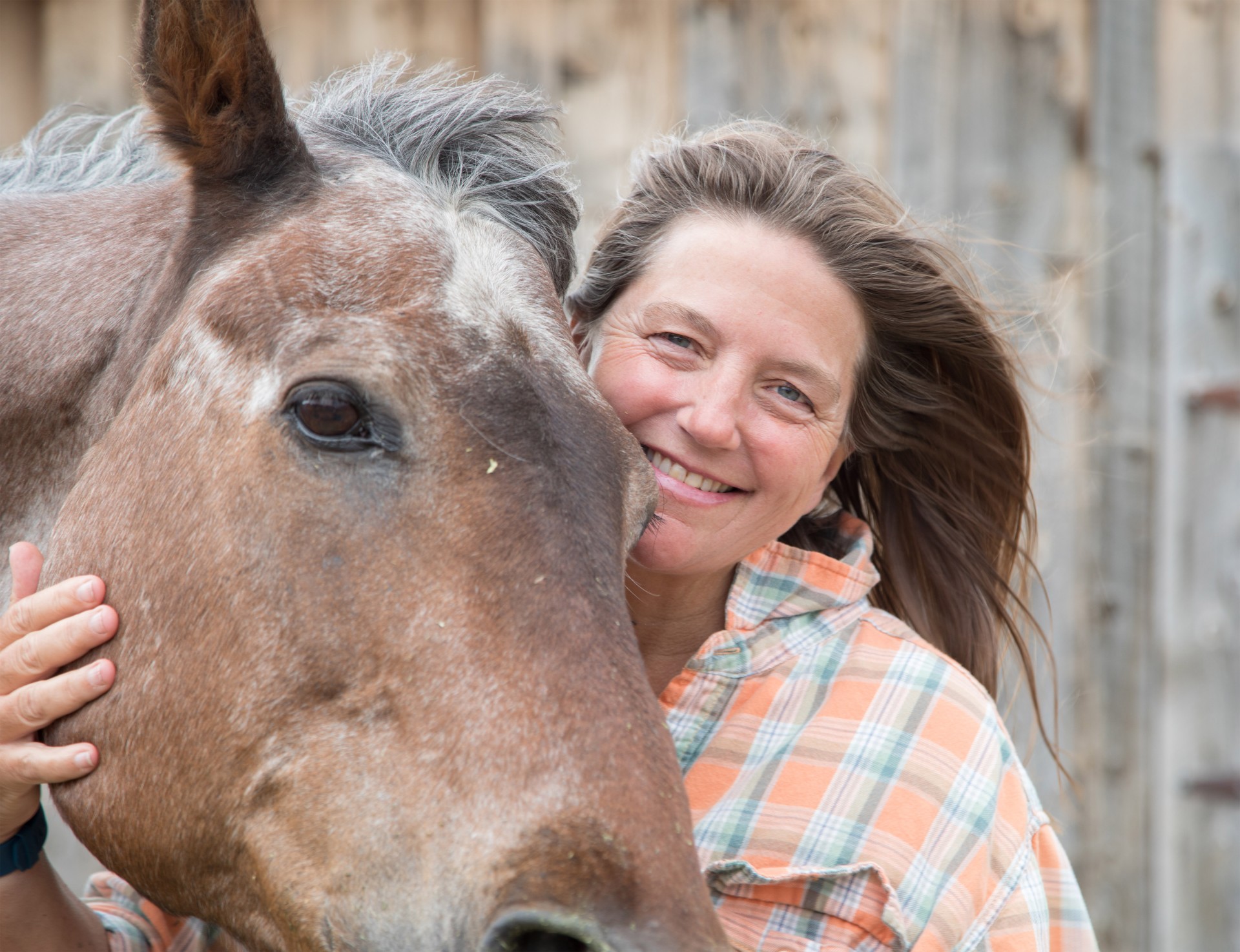 a woman smiling with her head on a horse