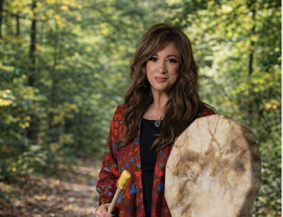 a woman holding a drum in the woods