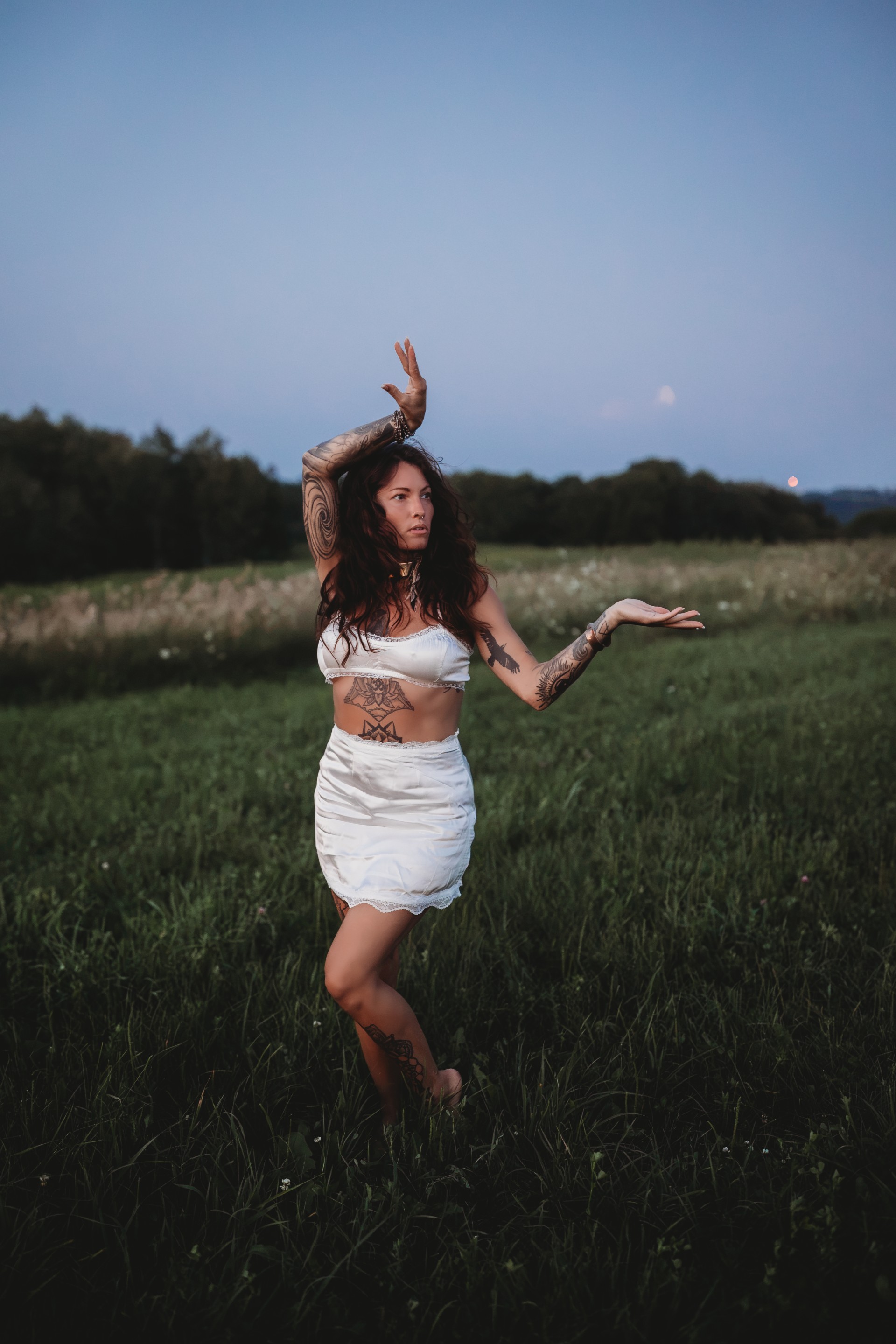 a woman in a white dress and garment standing in a field