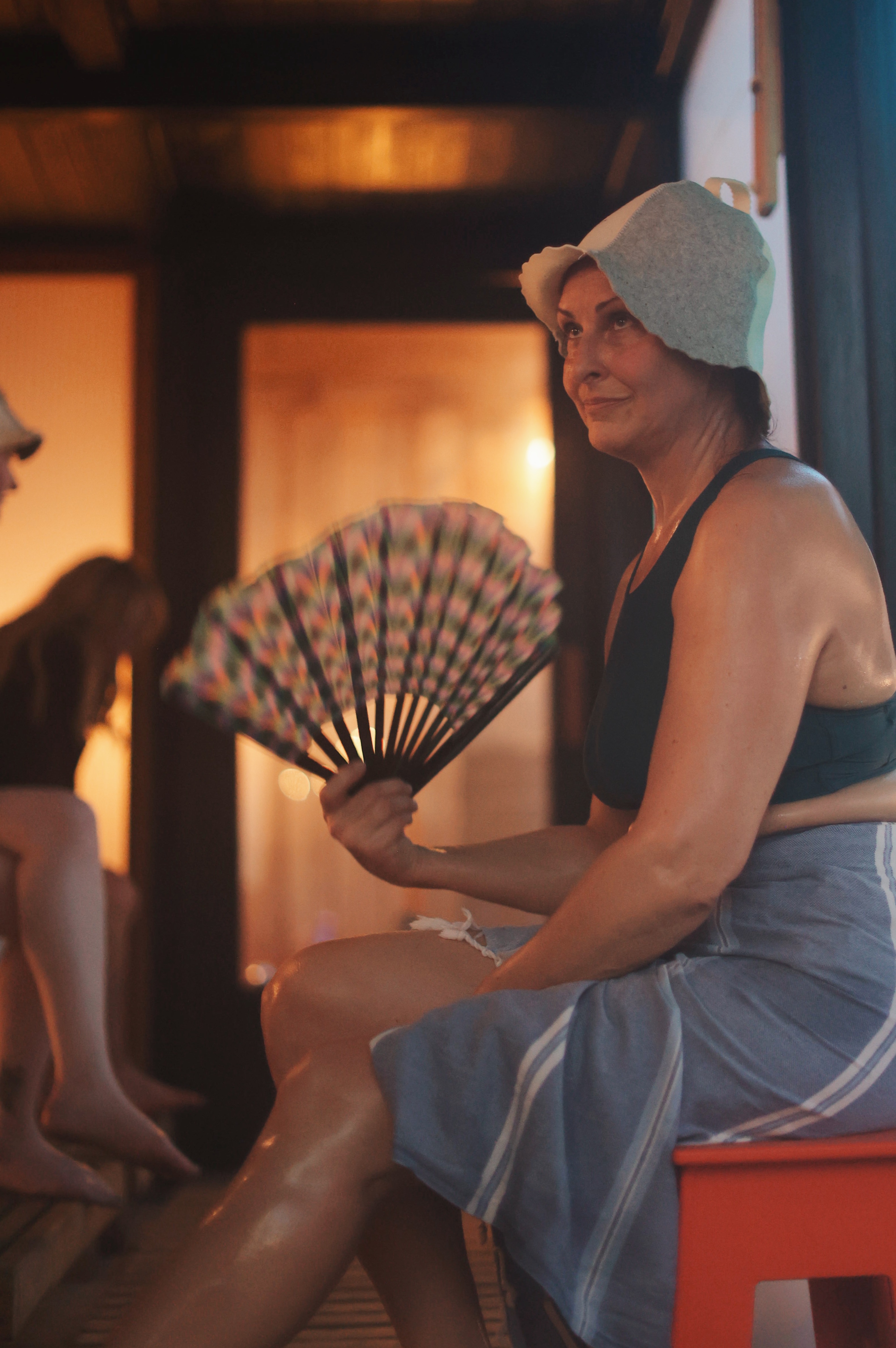 a woman sitting on a bench holding a fan