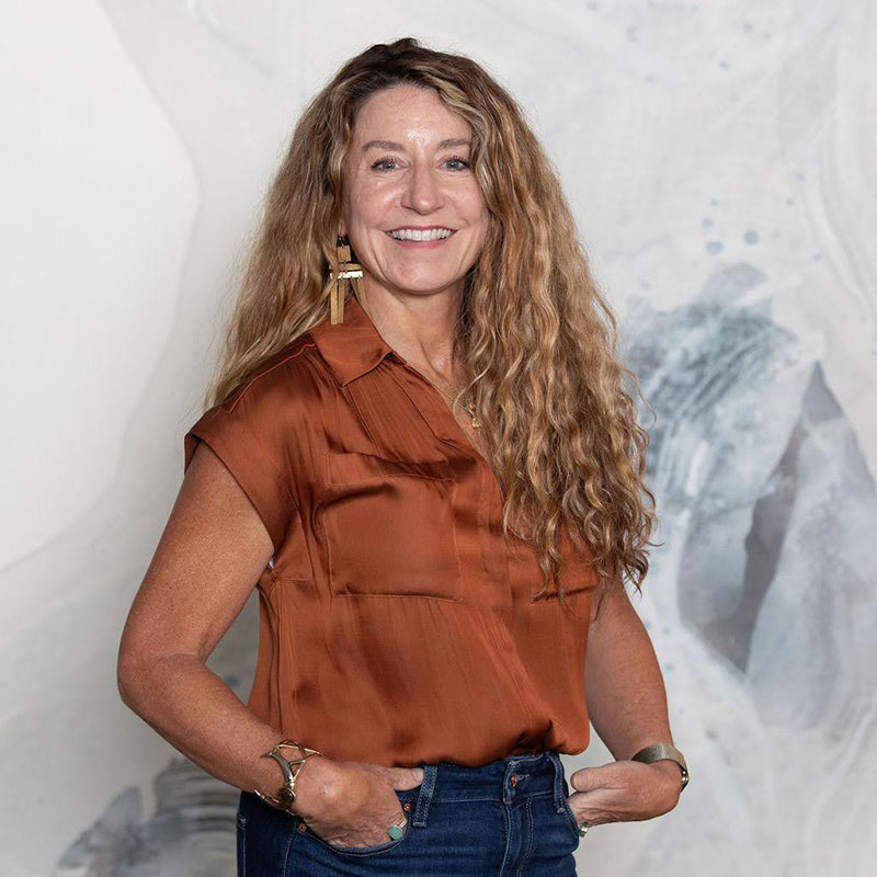 a woman with long hair wearing a brown blouse and blue jeans