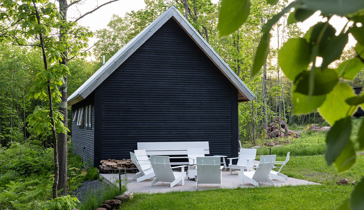 a black house with white chairs and a black building
