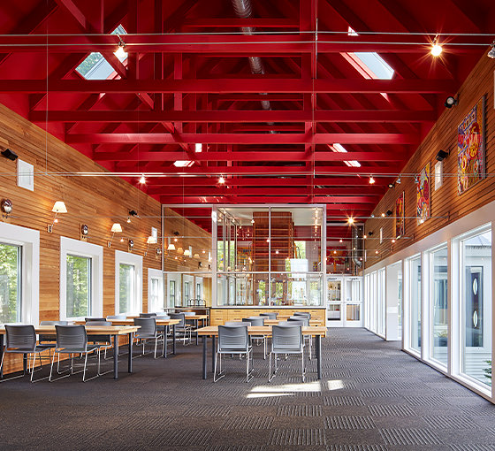 A large indoor space with red ceiling, wooden walls, and many windows.