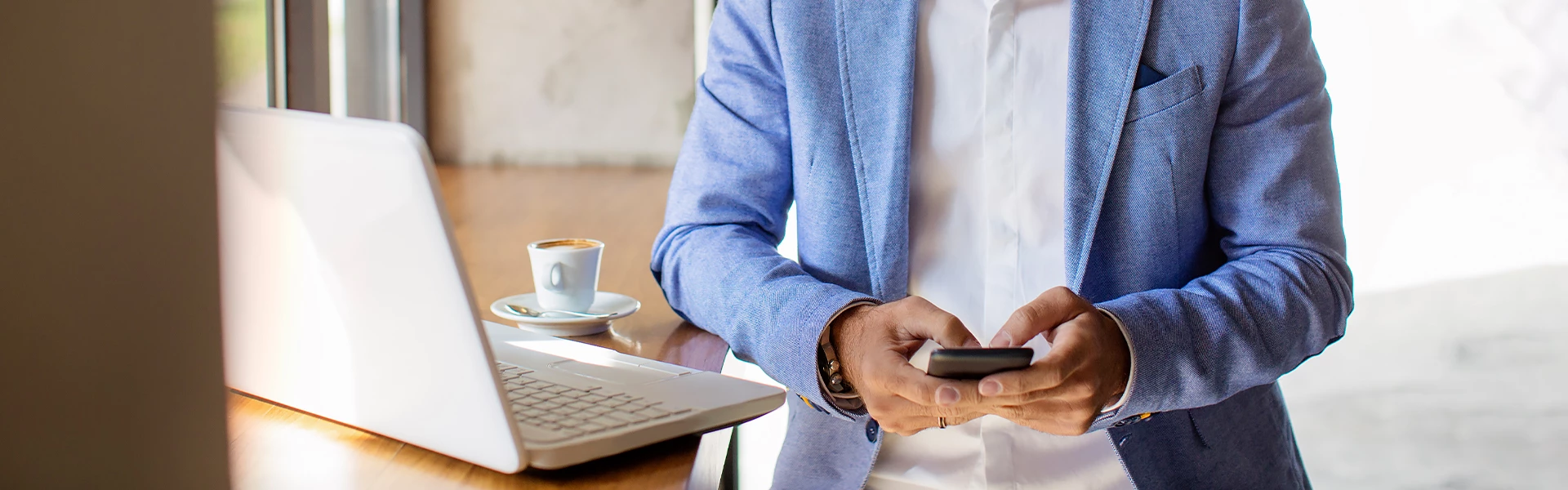 View of a man using his phone and his laptop