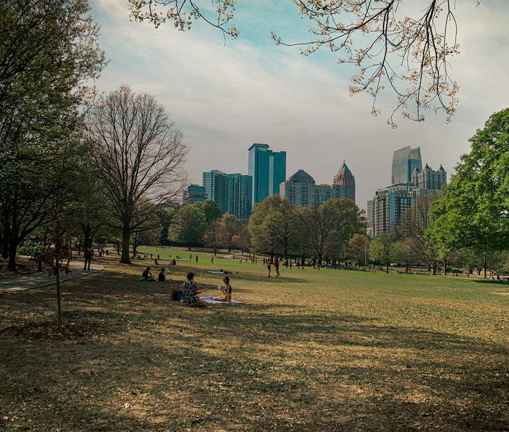 a park with people and trees and a city in the background