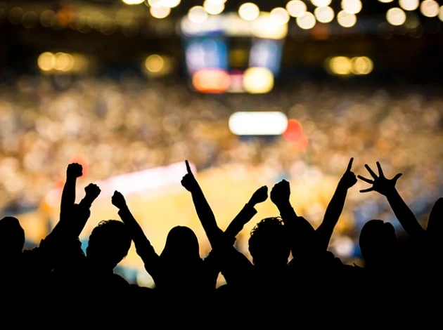 a crowd of people with their hands up in the air at an indoor arena