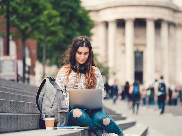 a woman sitting on a bench with a laptop at MIT university