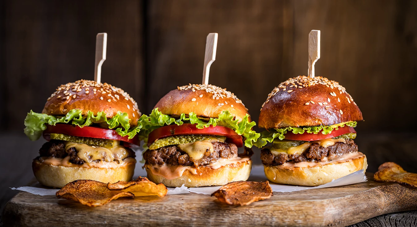 a group of burgers on a wood surface