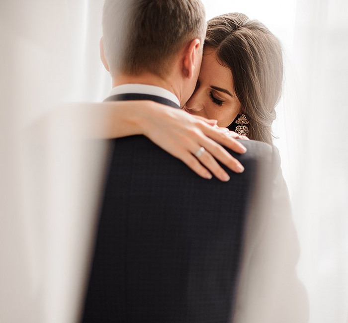 bride and groom in a warm embrace with bride's wedding ring in view