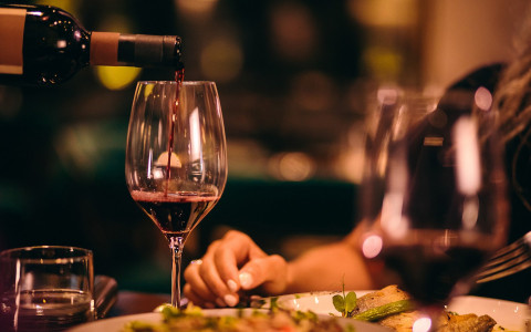 woman enjoying dinner with a glass of red wine