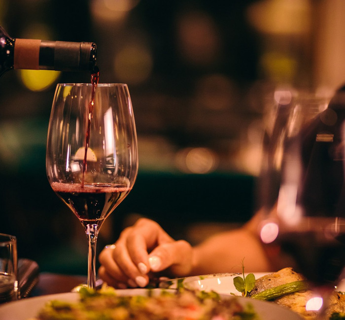 woman enjoying dinner with a glass of red wine