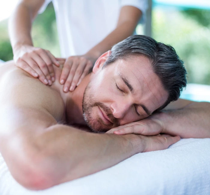 man with beard laying on table receiving a massage
