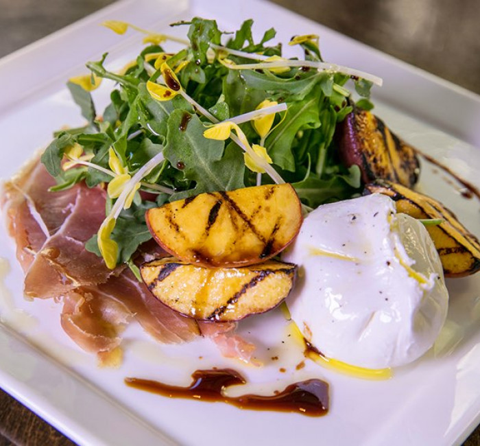 white square plate with prosciutto arugula salad and buffalo mozzarella 