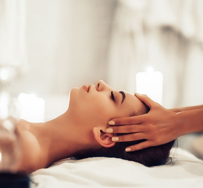 woman resting her head on a white towel and having her temples massaged 