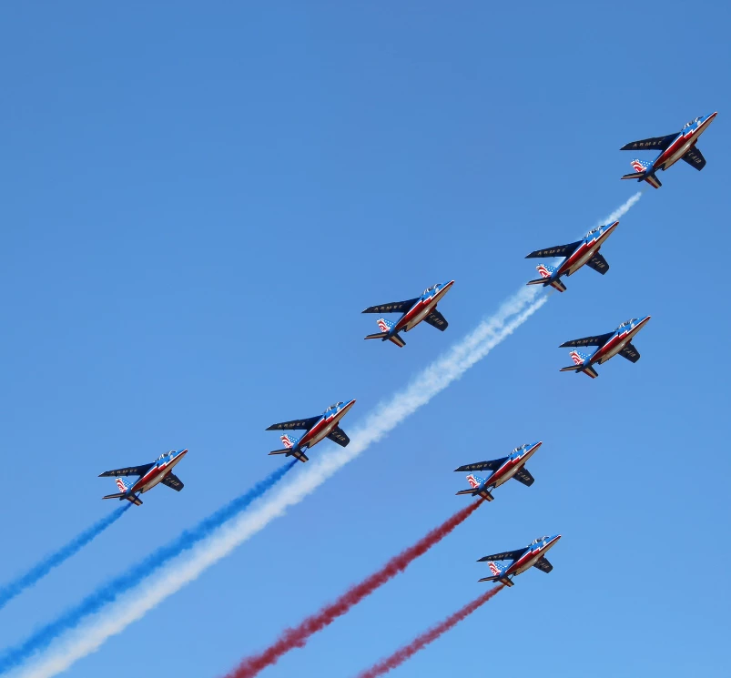a group of airplanes flying in formation with smoke trails