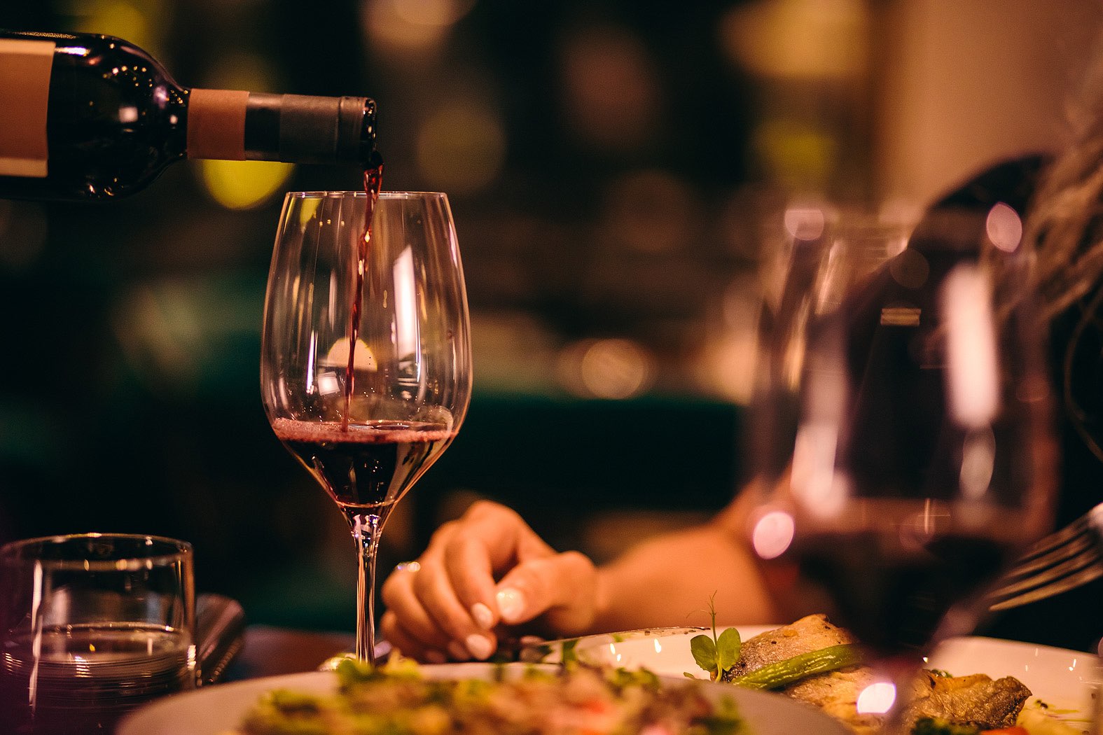 woman enjoying dinner with a glass of red wine