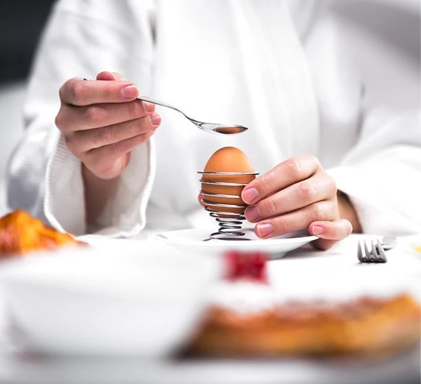 guest enjoying a room service breakfast in a white cotton robe