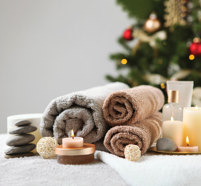 spa towels wrapped nicely on a bench next to a christmas tree