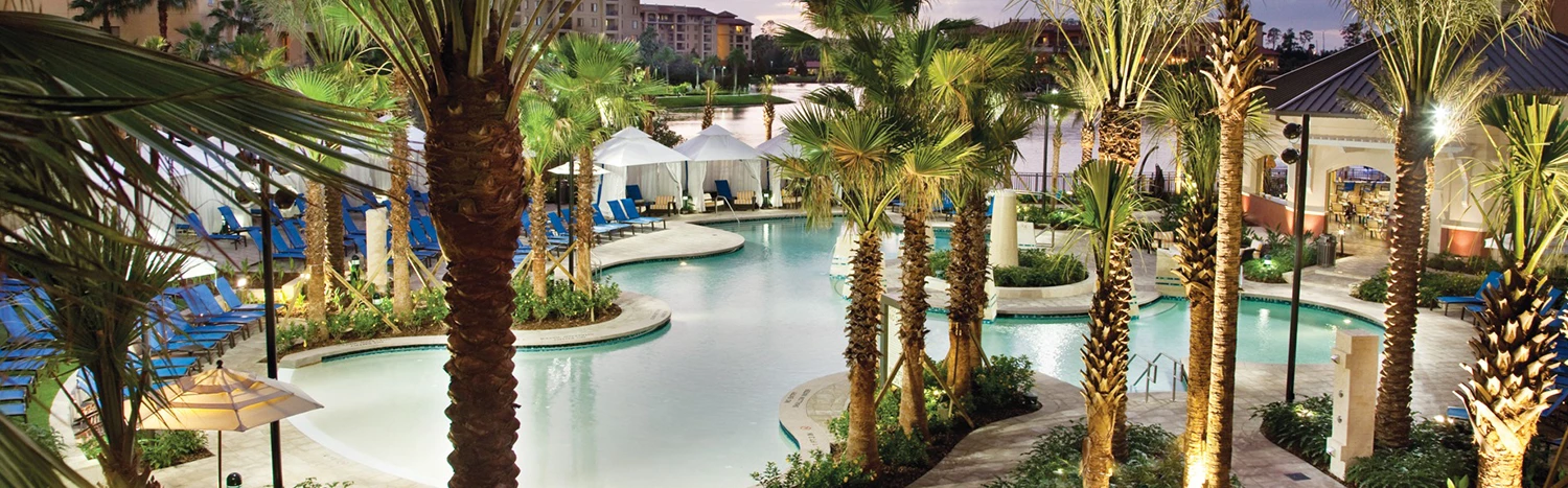 a pool with palm trees and a building in the background