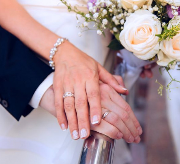 Close up of wedding couple hands on top of bouquet 