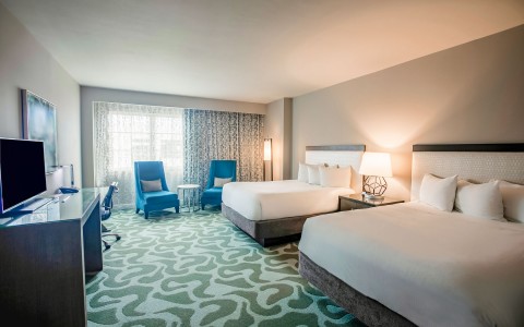 hotel room with double beds and two accent chairs