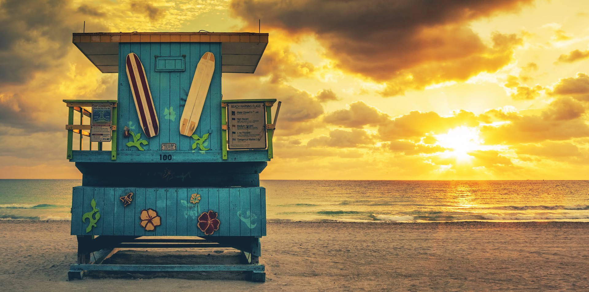 a blue lifeguard hut on a beach with surfboards on the front