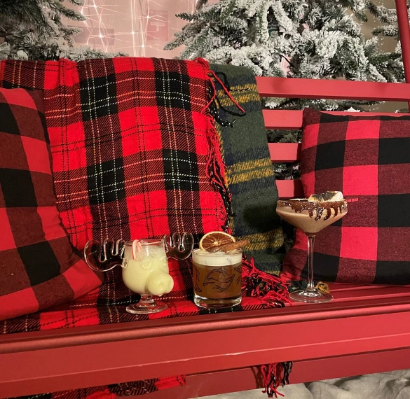 a red bench with drinks and plaid pillows