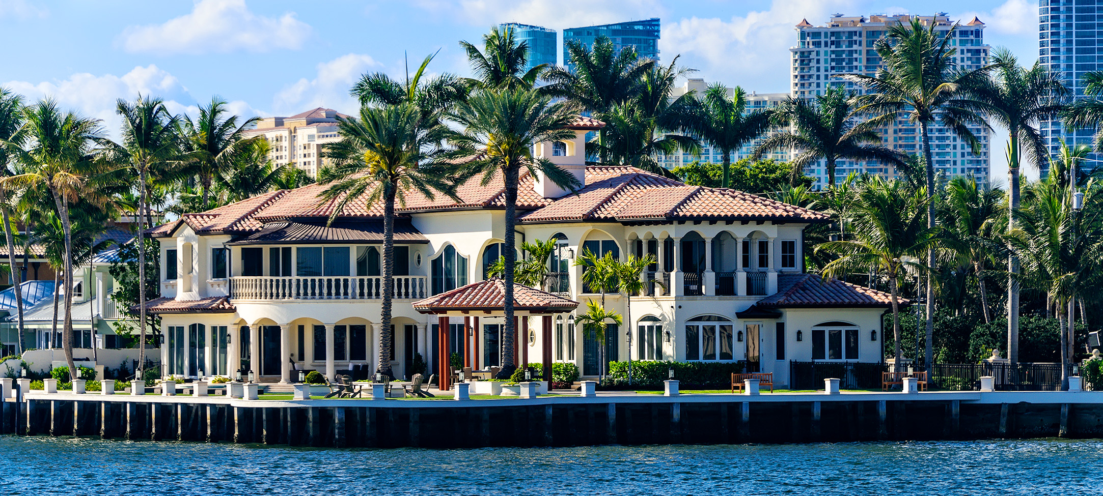 a large white house with palm trees and a body of water