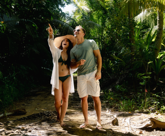 a man and woman in garment and hat standing in a forest