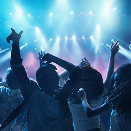 a group of people dancing in front of a bright stage