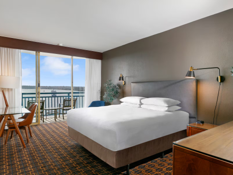 a room with a bed and a balcony overlooking a body of water